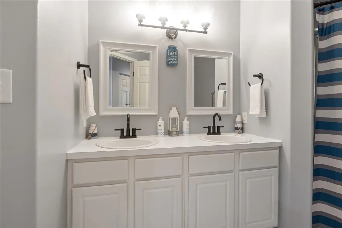A bright, modern bathroom with dual sinks, mirrors, contemporary lighting, and a fresh, clean ambiance. The space is designed for both functionality and relaxation, ideal for unwinding or preparing for a new day.