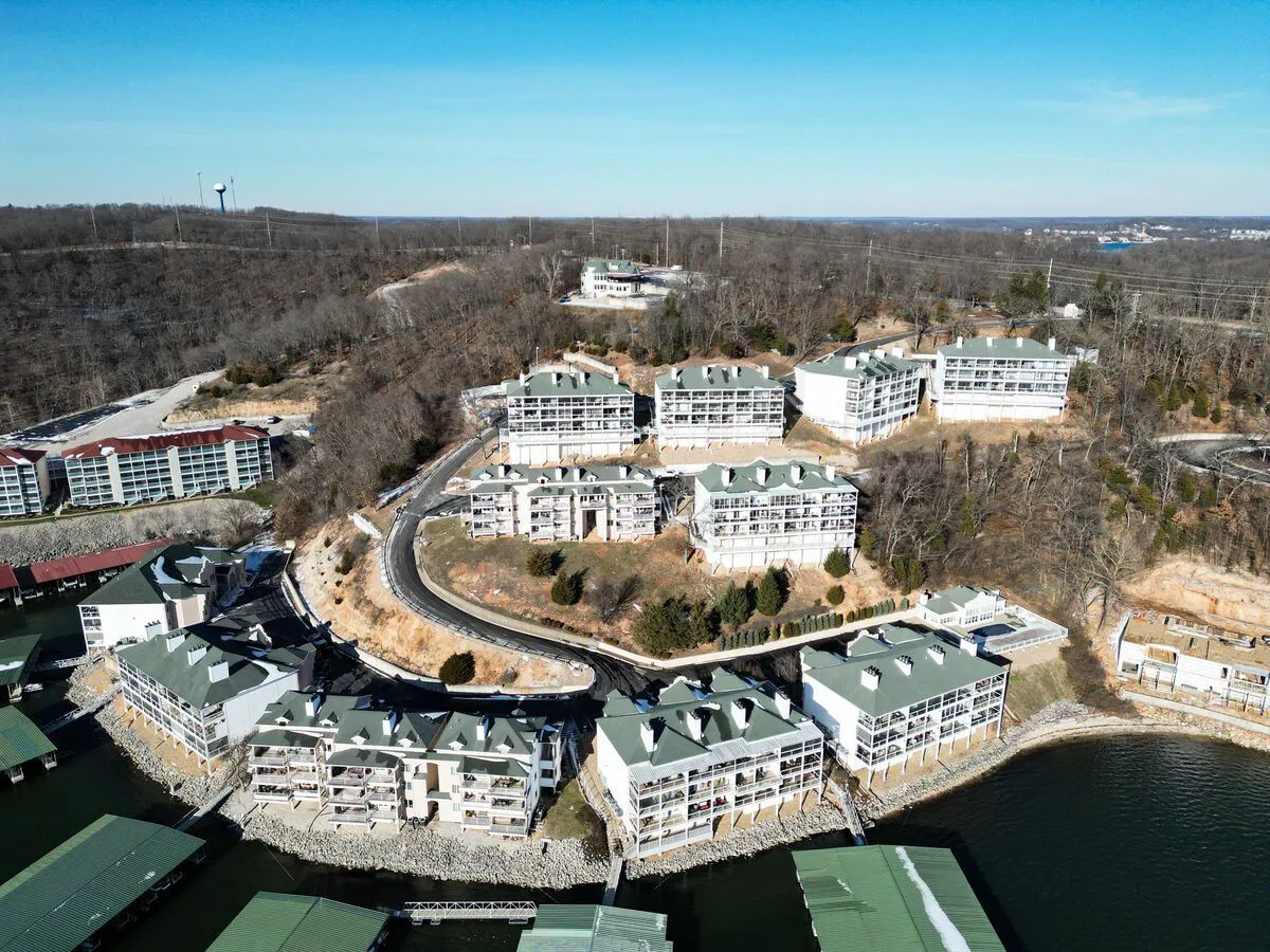 This exterior image captures waterfront buildings nestled against a backdrop of lush natural surroundings. The gently curving road hints at opportunities for scenic drives and exploration, while the water beckons for boating or lakeside relaxation.