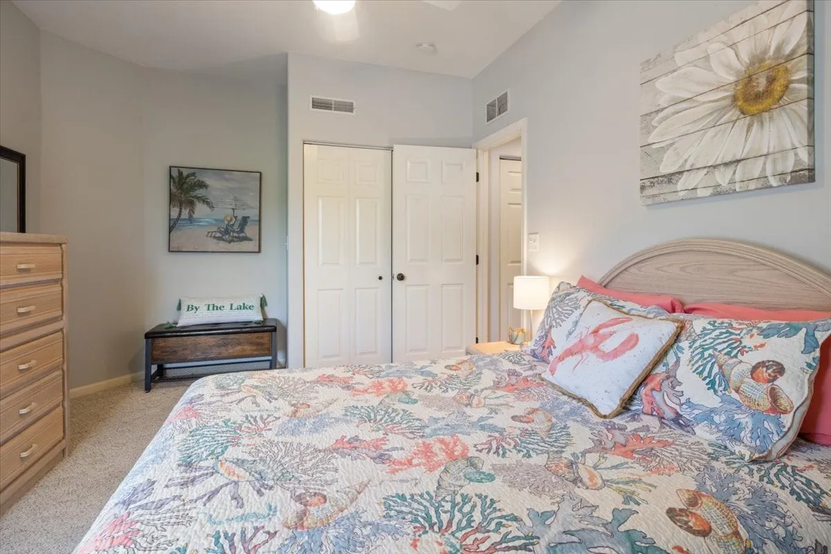 A cozy guest or family bedroom with a bed dressed in a colorful quilt, wall artwork, a dresser, and a lamp. The room exudes warmth and comfort, perfect for families or friends seeking a restful haven after a day of adventure.