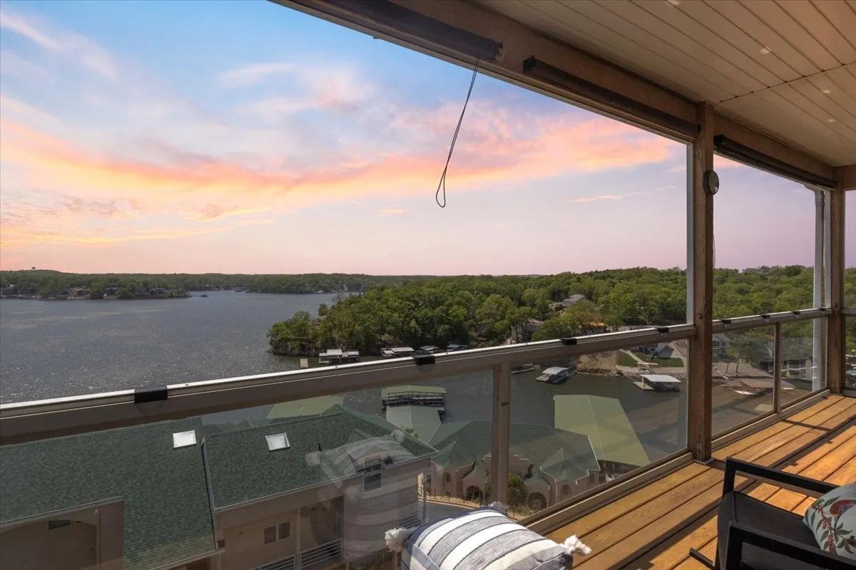 A stunning, expansive view over Lake Ozark at sunset, with comfortable outdoor seating perfectly positioned to enjoy the vibrant sky. The peaceful atmosphere suggests a place to relax after an evening out or to gather with friends for drinks while watching the sun dip below the horizon.