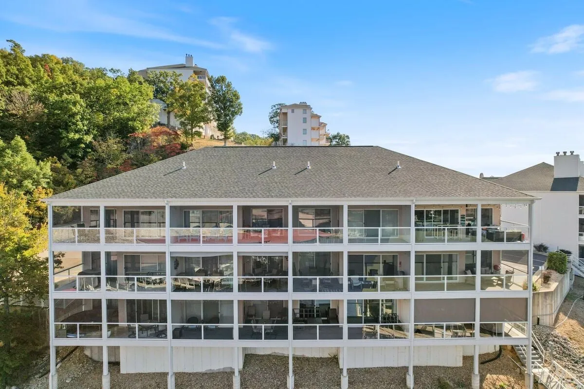 This exterior image highlights a multi-level balcony nestled against a landscaped hillside with surrounding buildings visible. The setting conveys a sense of elevation, seclusion, and natural beauty, emphasizing both privacy and connection with nature.